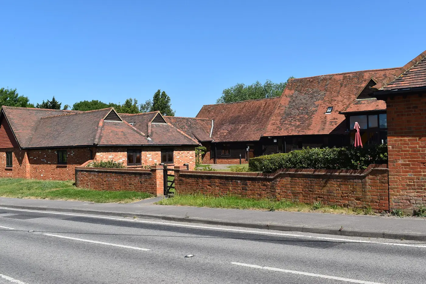 A long, single-storey converted brick and tile barn beside a road