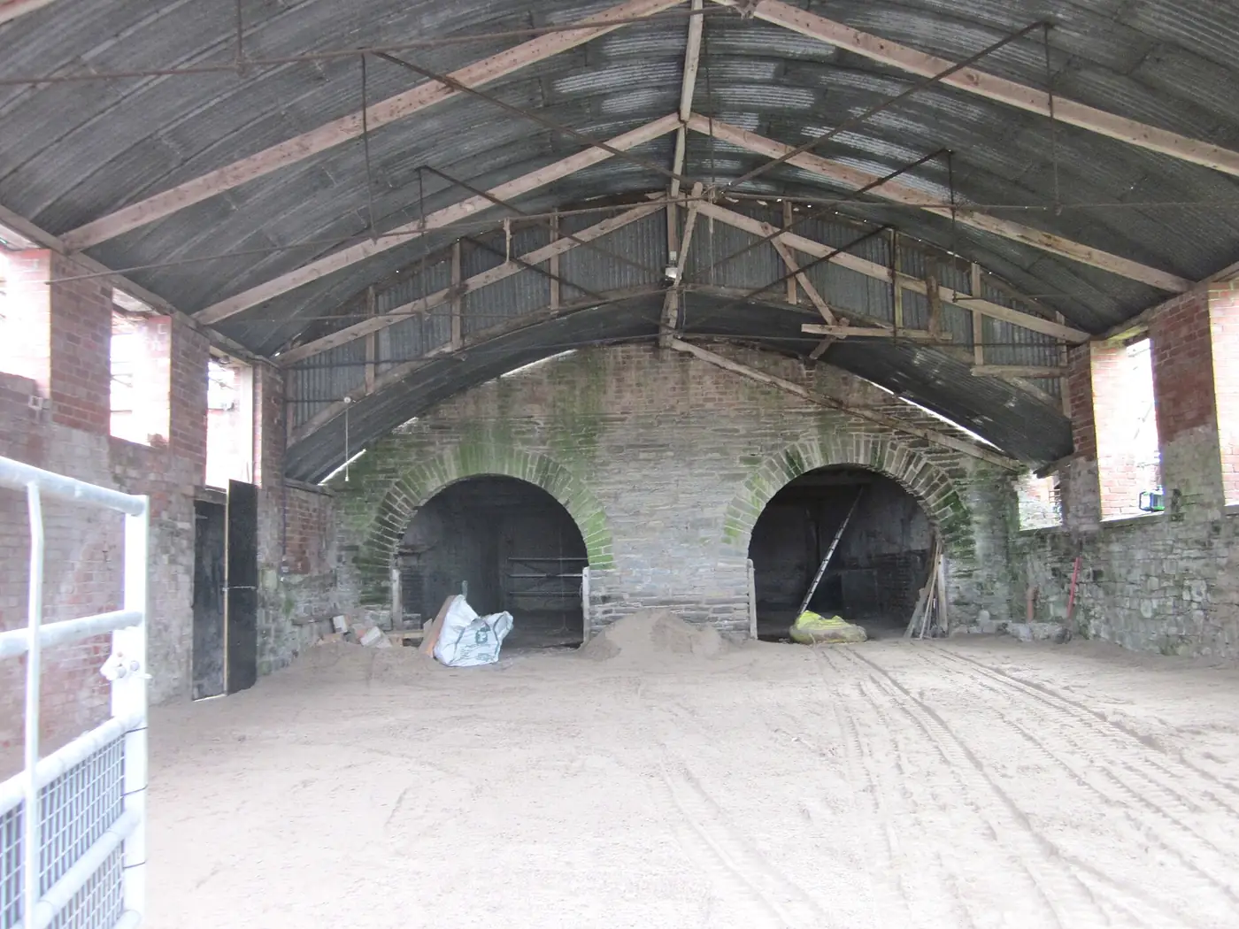 The interior of a large, empty farm storage building with a concrete floor and steel roof trusses