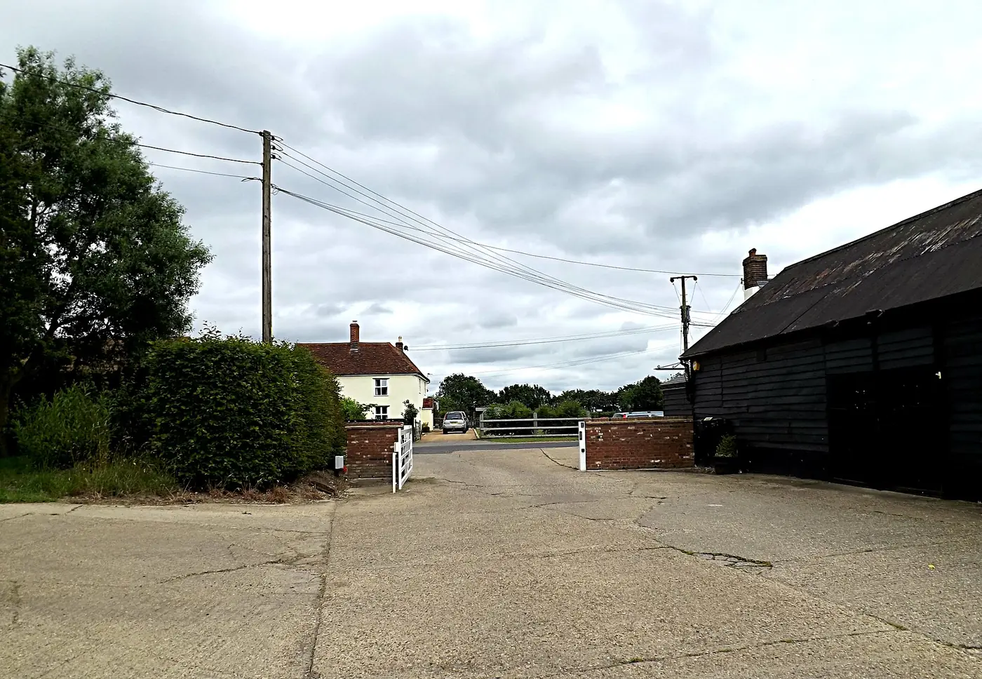 The entrance to a farm business park with a gravel drive, a gate and a black barn