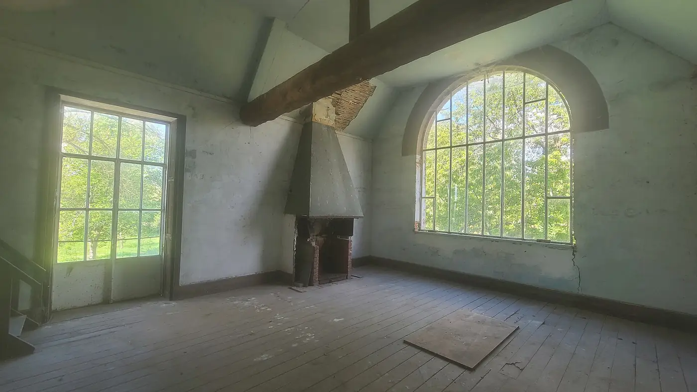 A bright, empty room with tall arched windows, white walls and exposed timber beams
