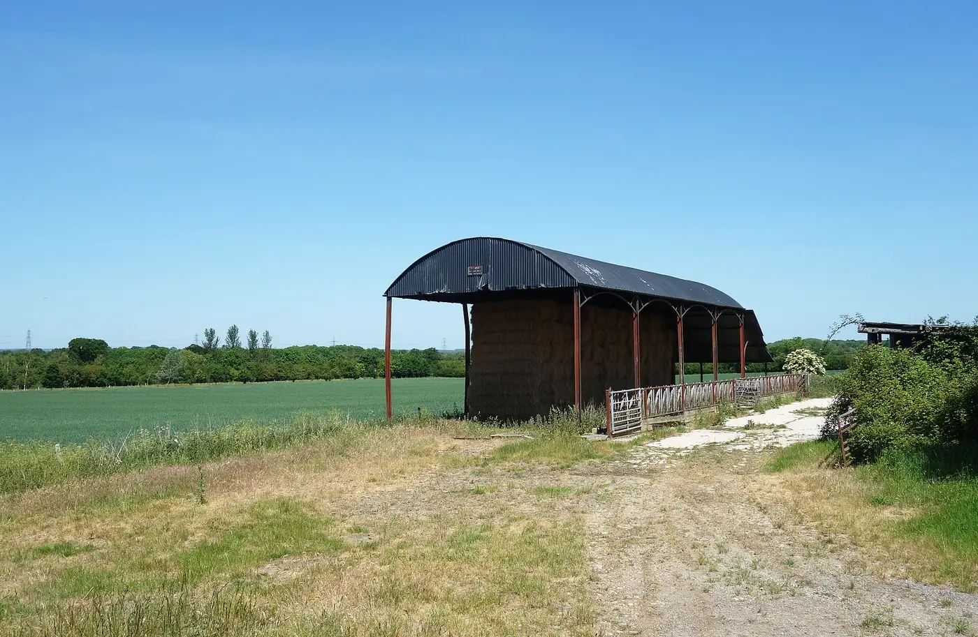 A Dutch barn with a curved roof standing in a farmyard