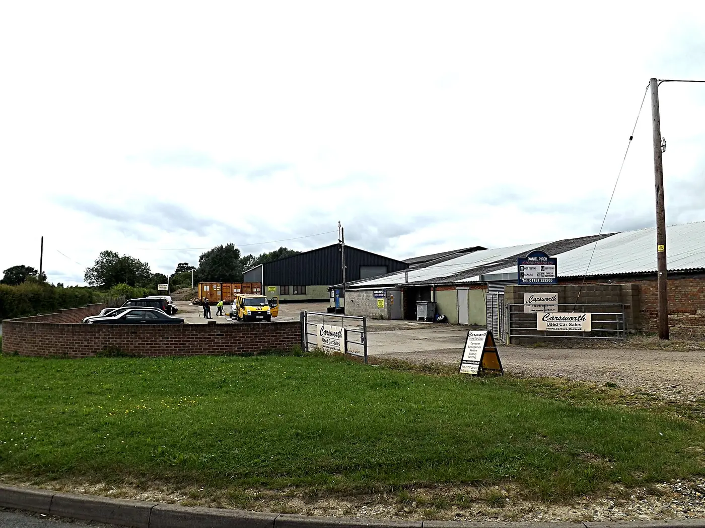 Farm business units behind a grass verge with business signs at the entrance