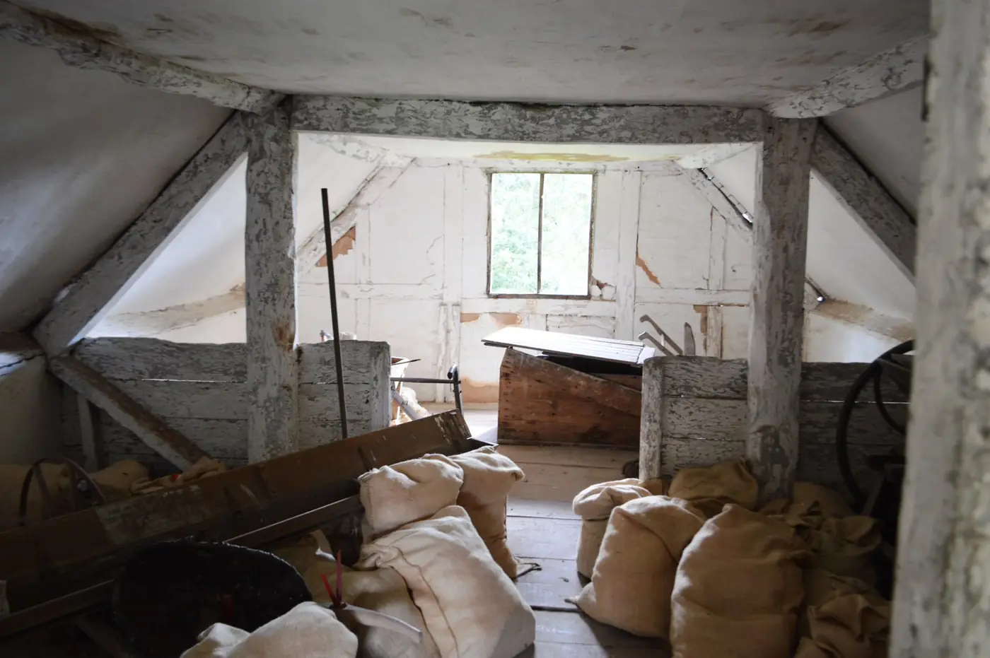 The inside of an old granary with timber beams, sacks and stored equipment waiting to be cleared
