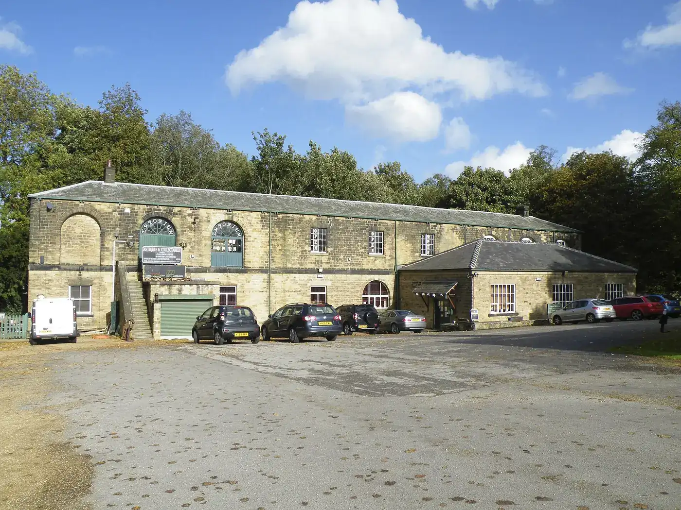 A row of single-storey stone workshops in a converted courtyard, with cars parked outside