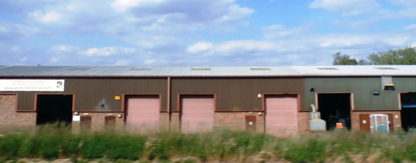 A row of modern business units with roller shutter doors beside a field
