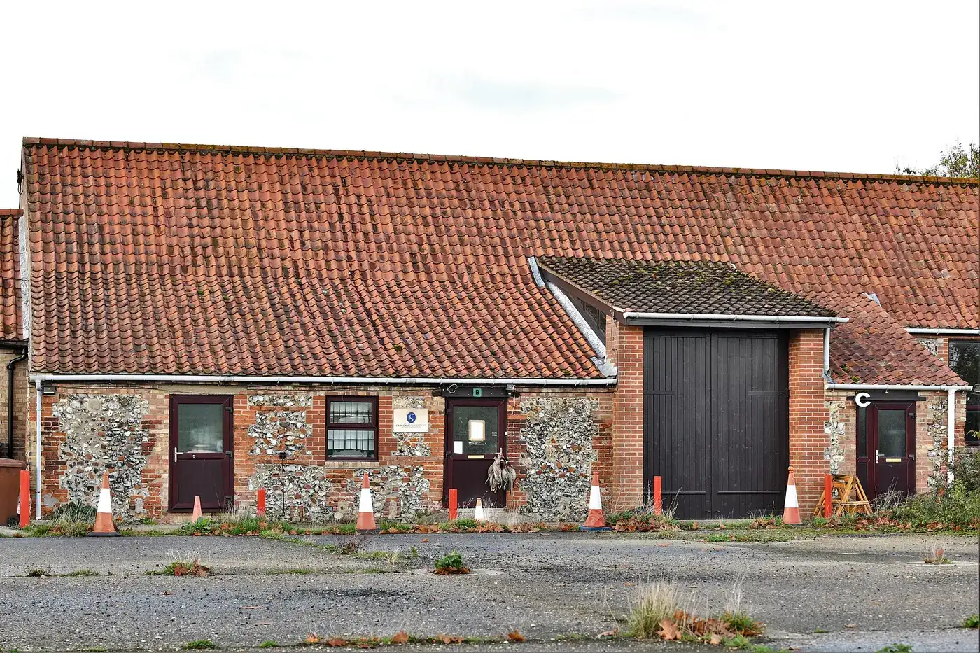 Single-storey flint and brick farm buildings converted into small business units around a yard