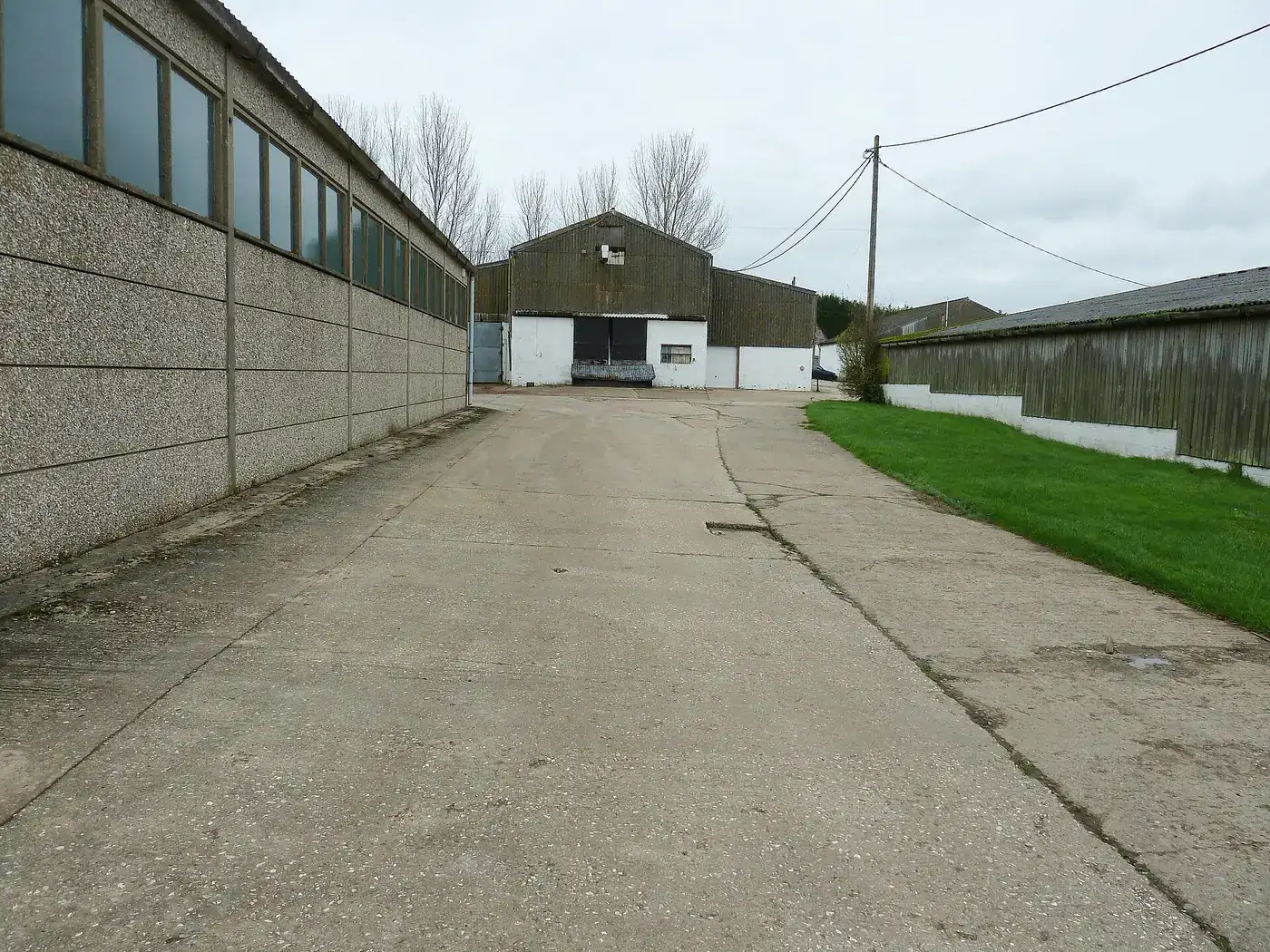 A large modern steel-framed agricultural building beside a concrete roadway