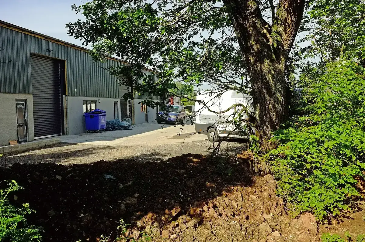 A modern steel-clad business unit with a roller shutter door and space for vehicles