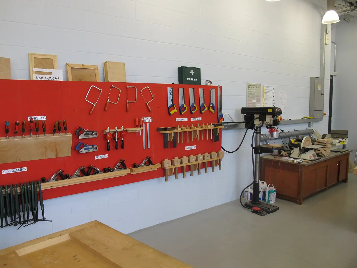 A well-equipped woodwork workshop with machinery, benches and tools on the wall